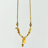 Gold necklace with leaf-shaped beads on a light gray background